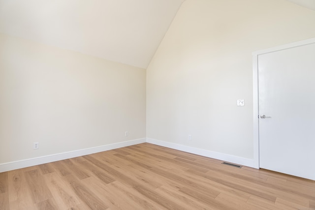 empty room featuring lofted ceiling, visible vents, light wood-style flooring, and baseboards