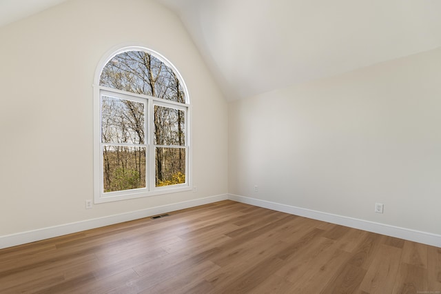 unfurnished room featuring visible vents, baseboards, vaulted ceiling, and light wood-type flooring