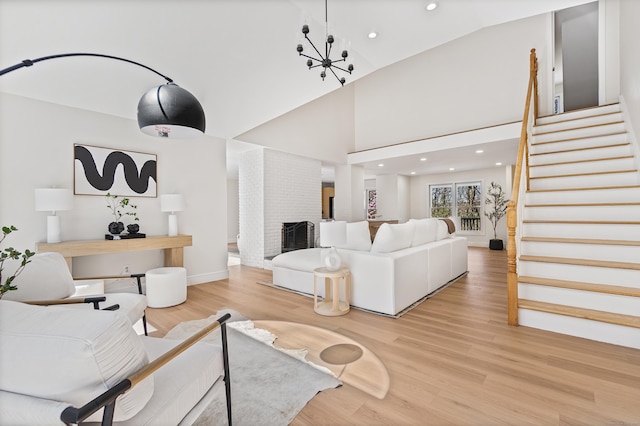 living room with a brick fireplace, recessed lighting, stairway, and light wood-style flooring