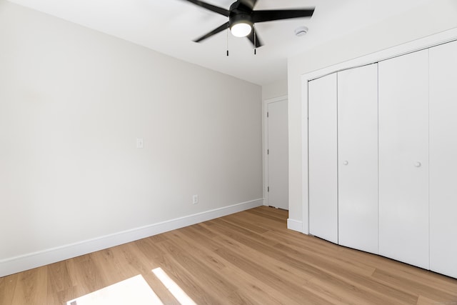 unfurnished bedroom with a closet, light wood-style flooring, a ceiling fan, and baseboards