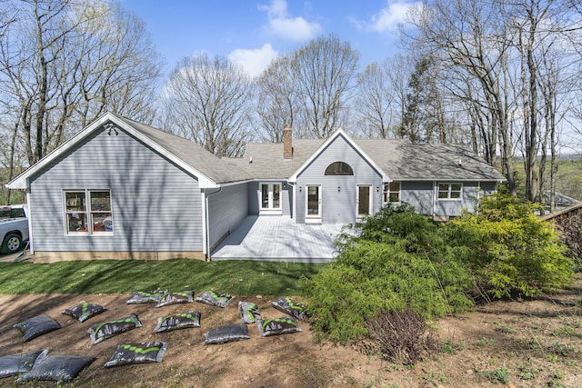 back of house featuring a lawn, a chimney, and a patio area