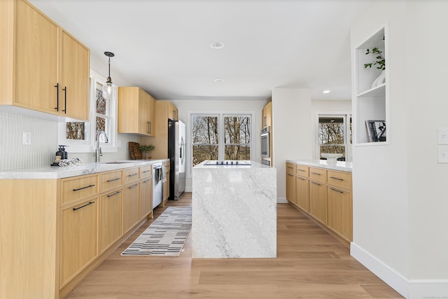 kitchen featuring plenty of natural light, appliances with stainless steel finishes, light wood finished floors, and a sink