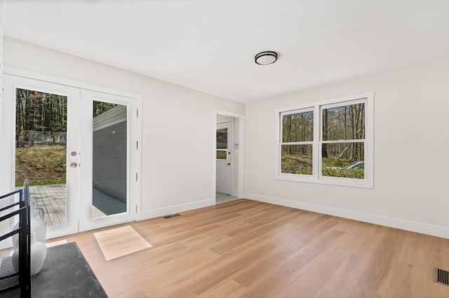 empty room with visible vents, light wood-type flooring, and baseboards