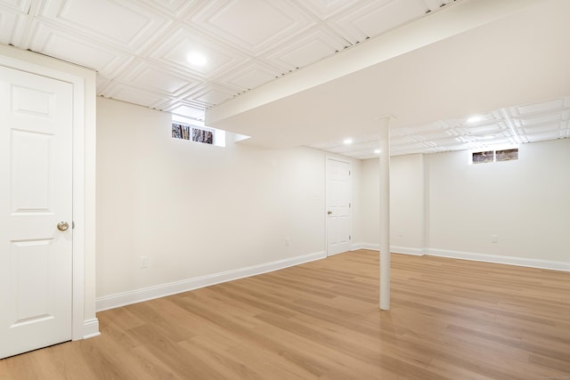 below grade area featuring an ornate ceiling, recessed lighting, light wood finished floors, and baseboards