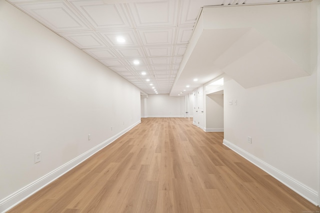finished below grade area with baseboards, recessed lighting, and light wood-style floors