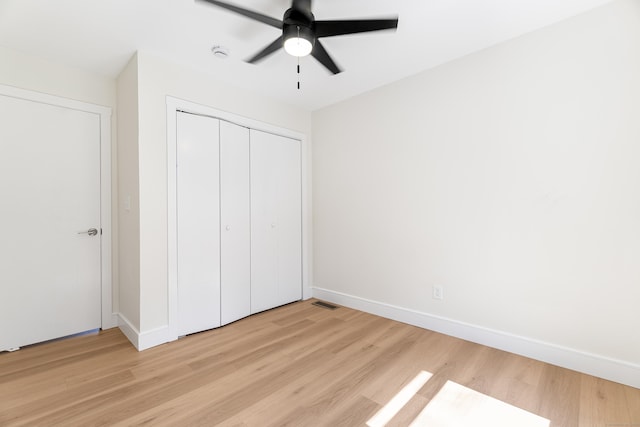unfurnished bedroom with a closet, ceiling fan, visible vents, light wood-style flooring, and baseboards