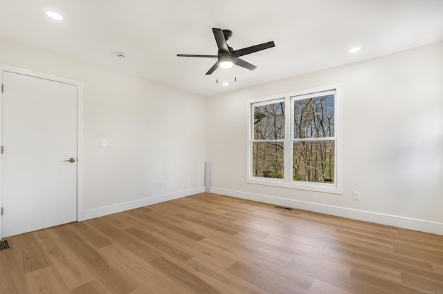 spare room featuring visible vents, a ceiling fan, light wood finished floors, and baseboards