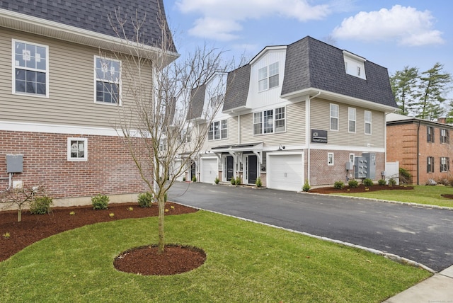 exterior space featuring roof with shingles, mansard roof, driveway, an attached garage, and a front lawn