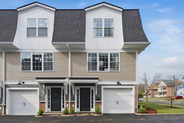 view of front of property featuring board and batten siding, driveway, a garage, and roof with shingles