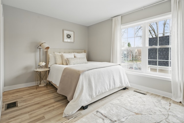 bedroom featuring wood finished floors, baseboards, and visible vents