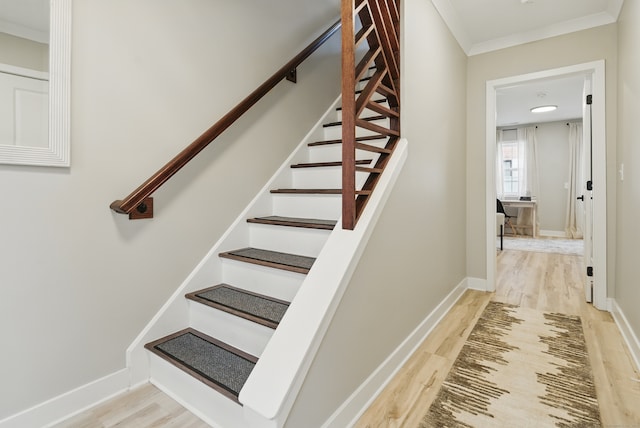 stairs with ornamental molding, baseboards, and wood finished floors