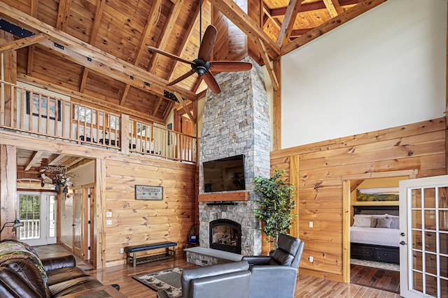 72 Indian Spring Rd, Woodstock, CT 06281 - living room with hardwood / wood-style flooring, wooden walls, a ceiling fan, high vaulted ceiling, and a stone fireplace
