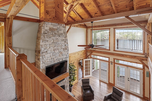 72 Indian Spring Rd, Woodstock, CT 06281 - unfurnished living room with beam ceiling, ceiling fan, a stone fireplace, wood ceiling, and french doors