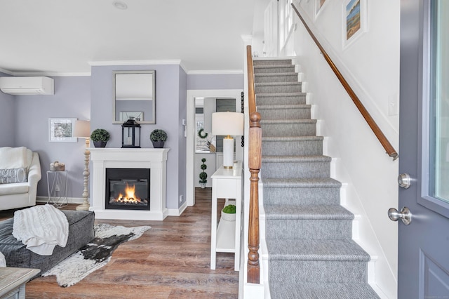 stairs featuring baseboards, wood finished floors, crown molding, and a wall unit AC