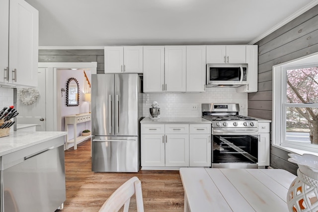 kitchen featuring decorative backsplash, white cabinetry, stainless steel appliances, and light wood finished floors