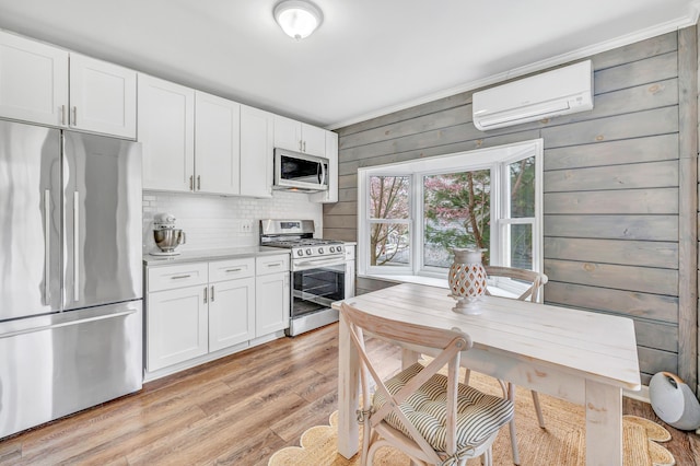 kitchen featuring appliances with stainless steel finishes, white cabinetry, and a wall unit AC