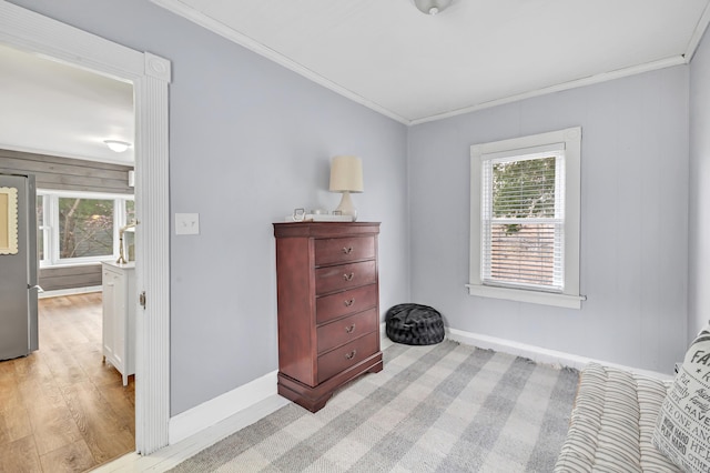 bedroom featuring freestanding refrigerator, light wood-style flooring, baseboards, and ornamental molding