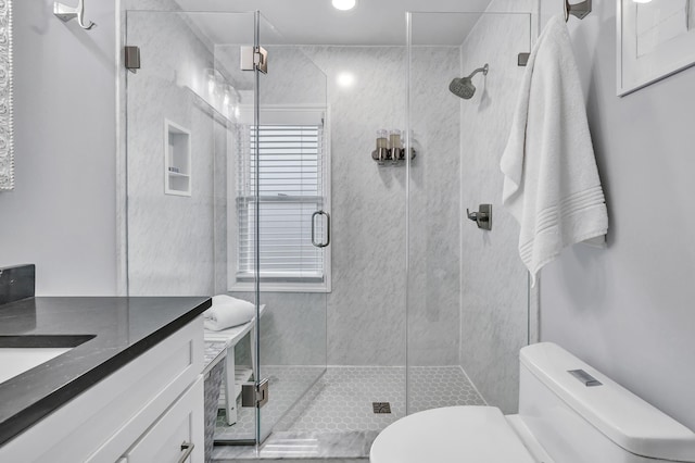 bathroom with a stall shower, vanity, and toilet
