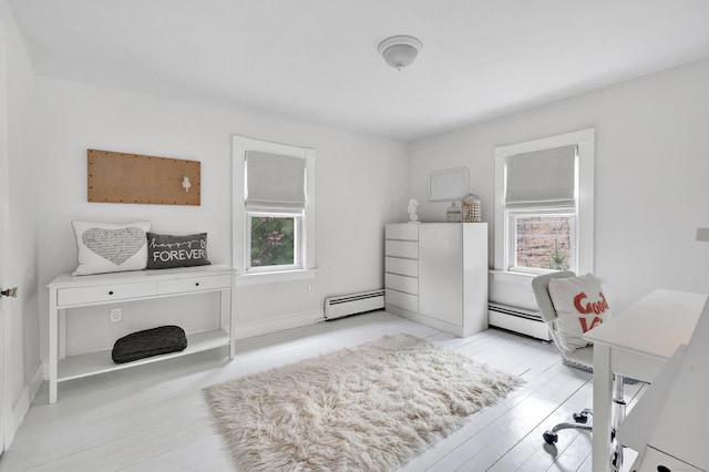 bedroom with a baseboard heating unit and light wood-style floors