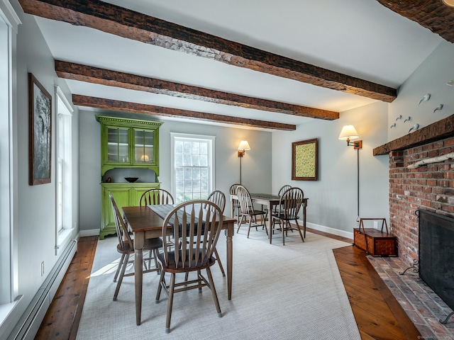 dining room featuring baseboards, a fireplace, beamed ceiling, wood finished floors, and a baseboard heating unit