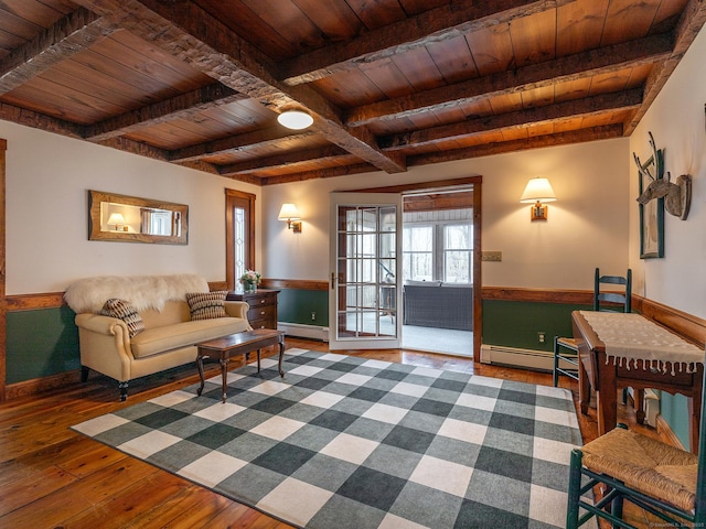 living area with wooden ceiling, a baseboard heating unit, wood-type flooring, and a wainscoted wall