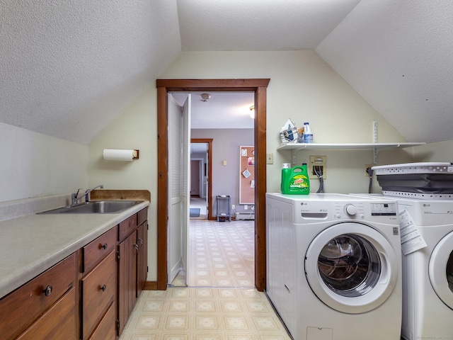 clothes washing area featuring light floors, a textured ceiling, a sink, washer and dryer, and cabinet space