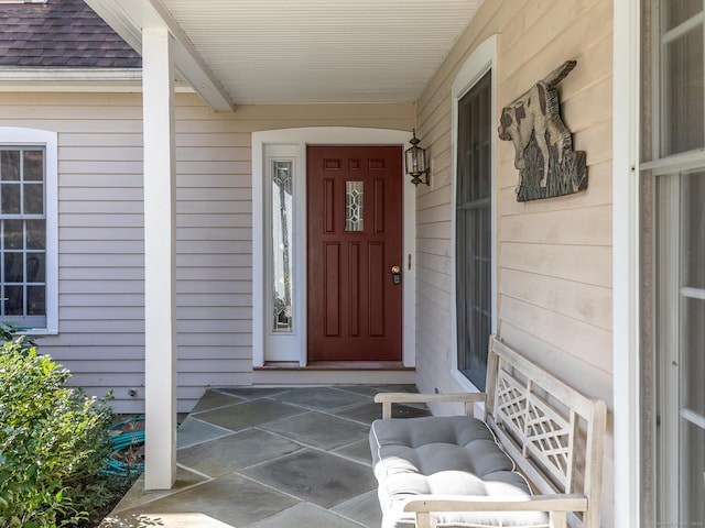 property entrance featuring a shingled roof and covered porch