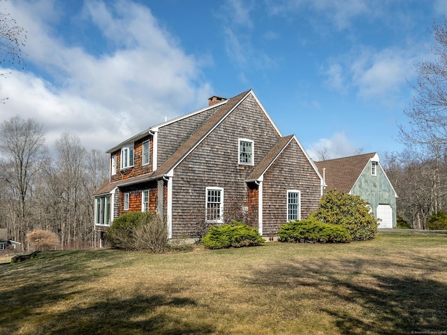 view of side of property featuring a shingled roof, a chimney, and a lawn