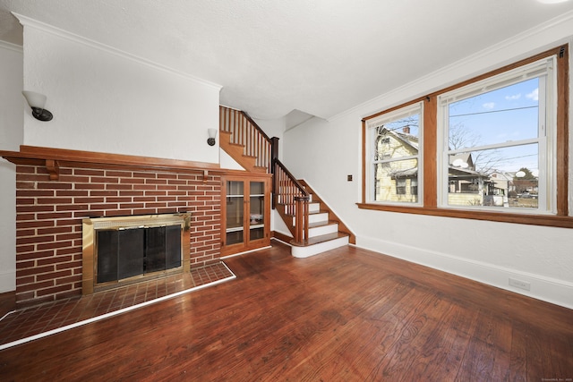 639 Cooke St, Waterbury, CT 06710 - unfurnished living room with hardwood / wood-style floors, crown molding, a brick fireplace, and stairs