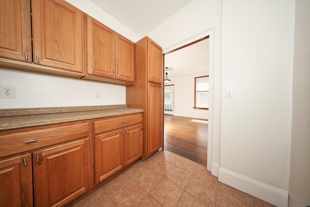639 Cooke St, Waterbury, CT 06710 - kitchen featuring brown cabinetry, light tile patterned floors, light countertops, and baseboards