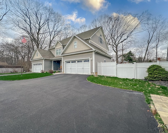 view of front of home with an attached garage, driveway, and fence