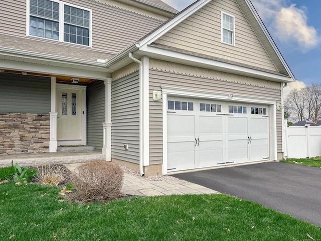 exterior space with fence, aphalt driveway, a shingled roof, and a garage