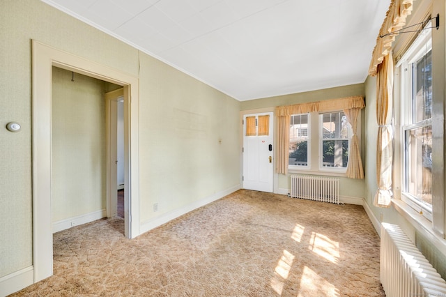 spare room with carpet, baseboards, ornamental molding, and radiator