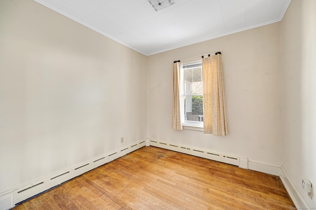 spare room featuring wood-type flooring, baseboard heating, and crown molding