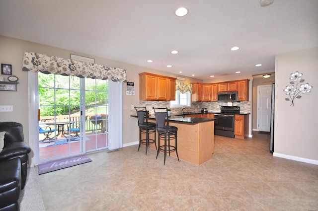 kitchen with a peninsula, open floor plan, a kitchen breakfast bar, electric range oven, and stainless steel microwave