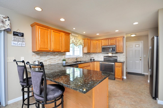 kitchen featuring appliances with stainless steel finishes, a sink, a breakfast bar area, a peninsula, and backsplash