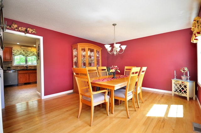 dining room featuring light wood-style floors, baseboards, visible vents, and a chandelier