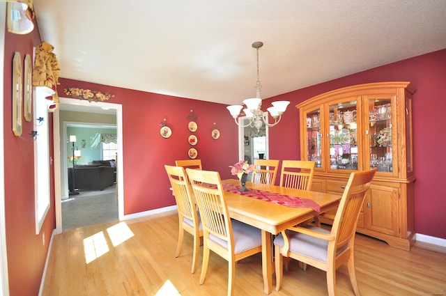 dining space featuring baseboards, an inviting chandelier, and light wood-type flooring