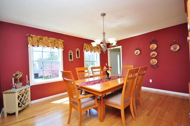 dining area featuring baseboards, a chandelier, and light wood finished floors
