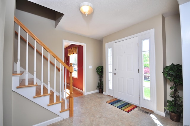 foyer with stairs, baseboards, and visible vents
