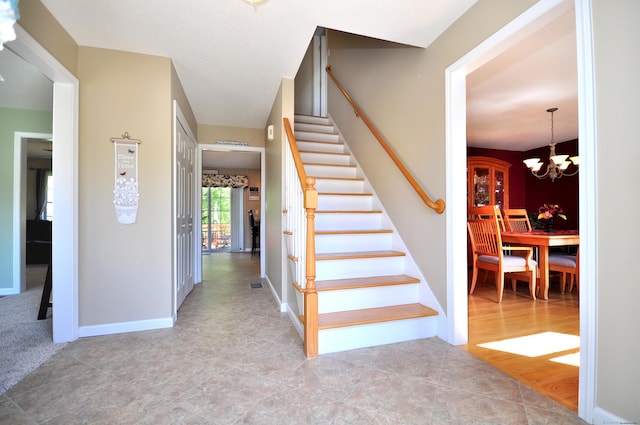 stairway with baseboards and a chandelier