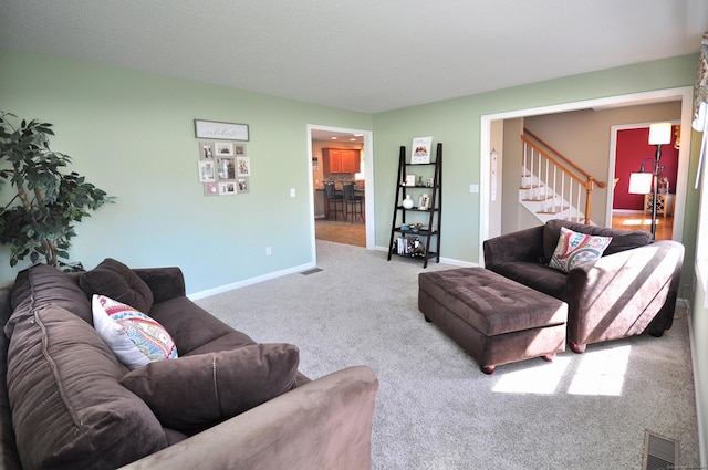 carpeted living area featuring stairway, baseboards, and visible vents