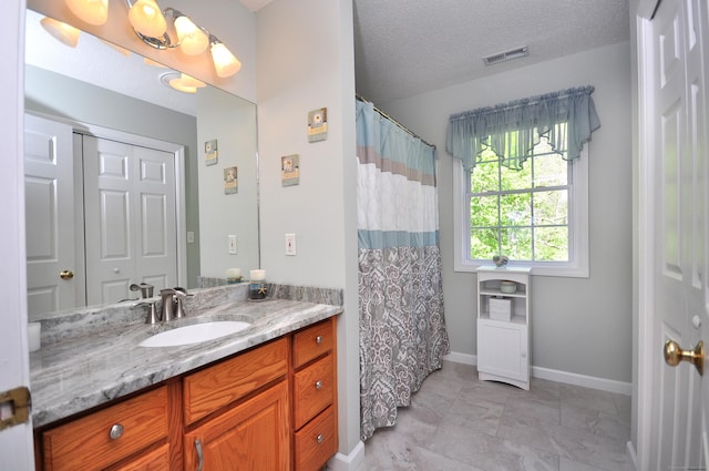 bathroom with visible vents, vanity, curtained shower, baseboards, and a textured ceiling
