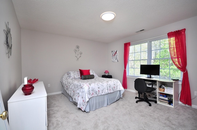 bedroom featuring a textured ceiling, light colored carpet, baseboards, and visible vents