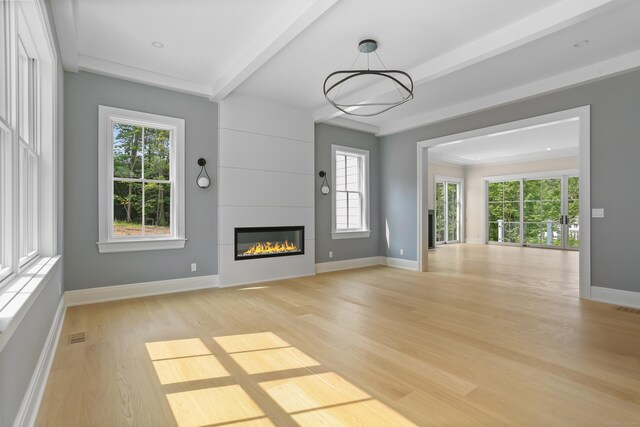 11 Tierney Ln, Westport, CT 06880 - unfurnished living room with beam ceiling, plenty of natural light, light wood-style flooring, a fireplace, and a chandelier