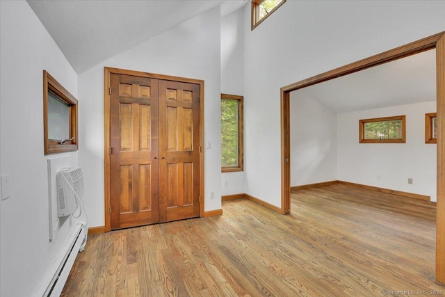 89 E St, Morris, CT 06763 - foyer entrance with a baseboard heating unit, light wood-type flooring, baseboards, a wall mounted AC, and high vaulted ceiling