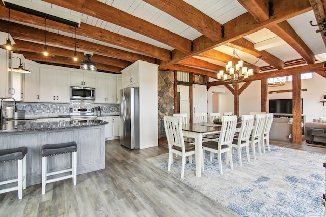 75 N Main St, East Hampton, CT 06424 - kitchen with stainless steel appliances, backsplash, light wood-style flooring, white cabinetry, and beamed ceiling