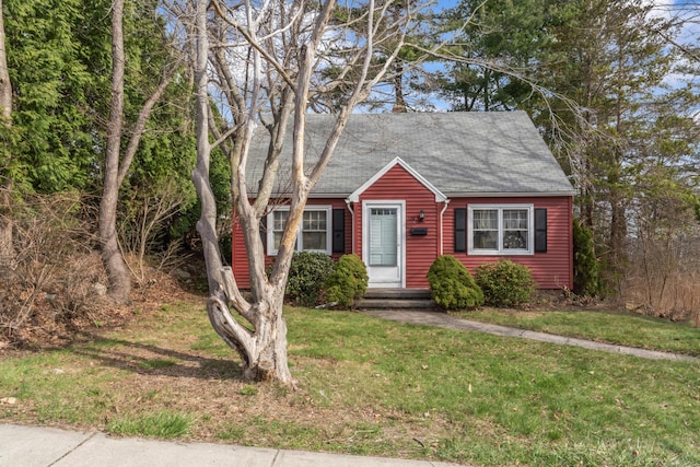 view of front of property featuring a shingled roof and a front lawn