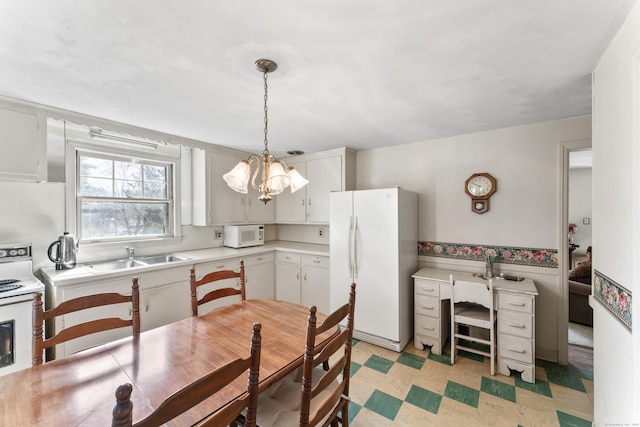 kitchen featuring an inviting chandelier, white appliances, light countertops, light floors, and a sink