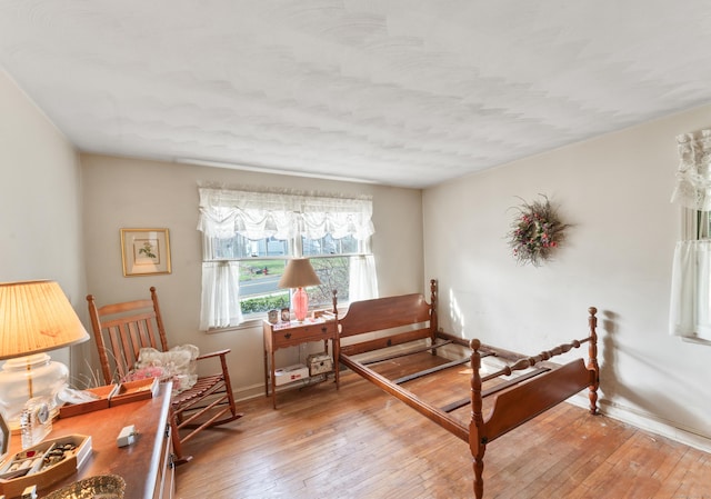 bedroom with wood-type flooring and baseboards